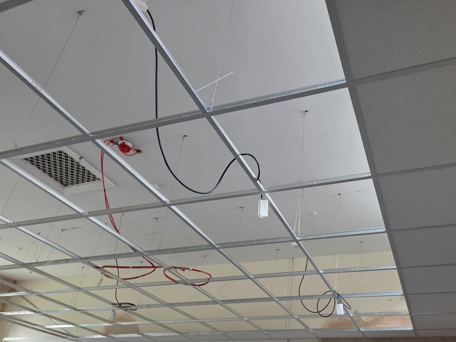 A new suspended ceiling grid with the first tiles fitted along one wall