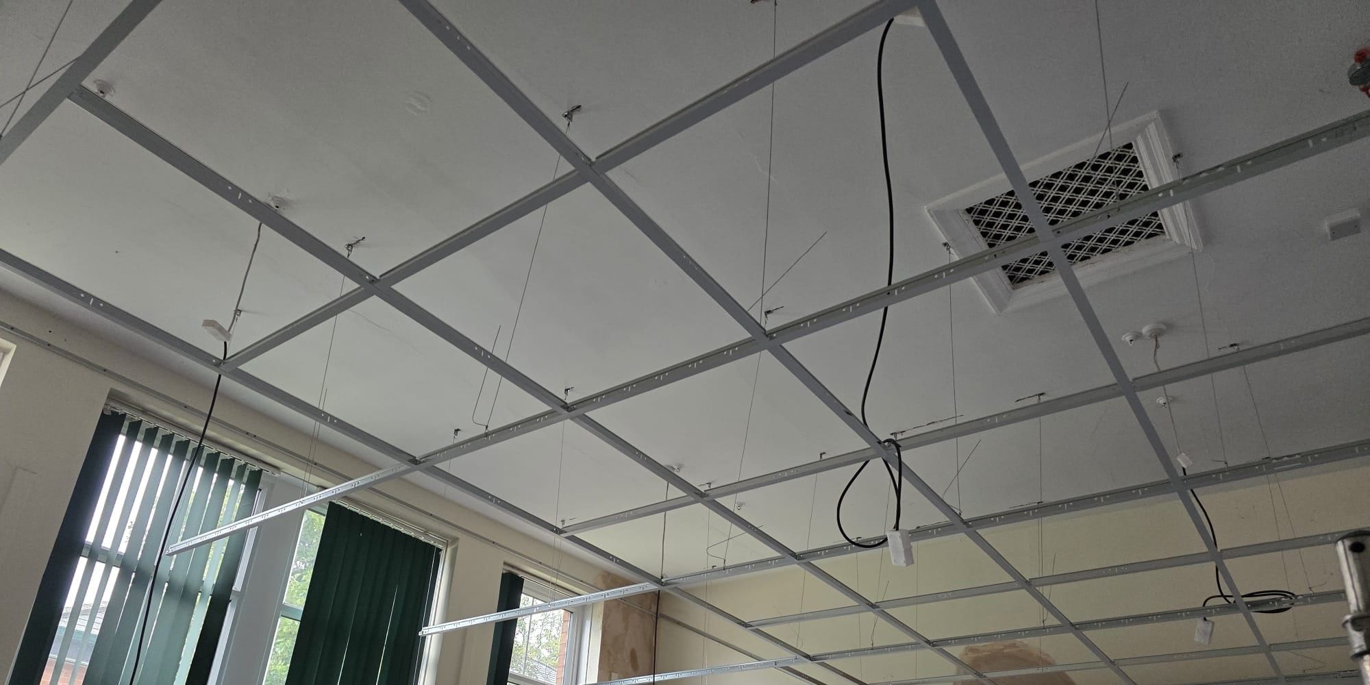 Main runners and cross tees of a new ceiling grid, hung level