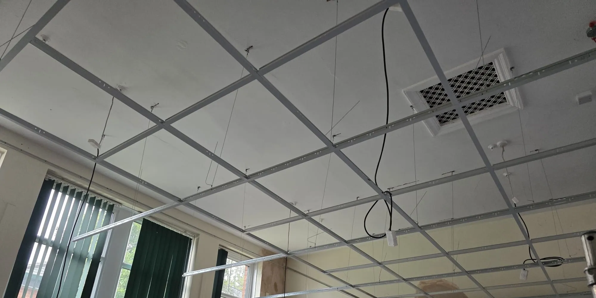 Main runners and cross tees of a new suspended ceiling grid, hung level