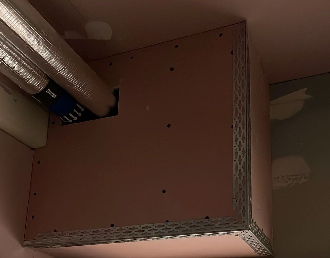 A bulkhead boxed in with pink fire-rated plasterboard and metal corner beads