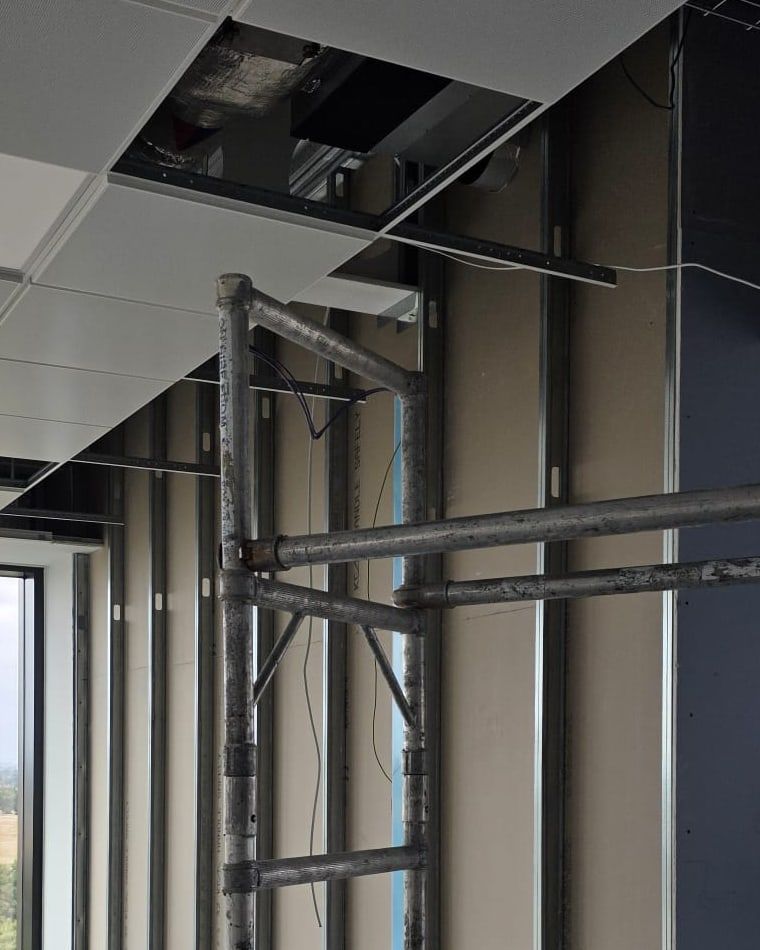 Metal studs fixed between floor and ceiling track beside large windows